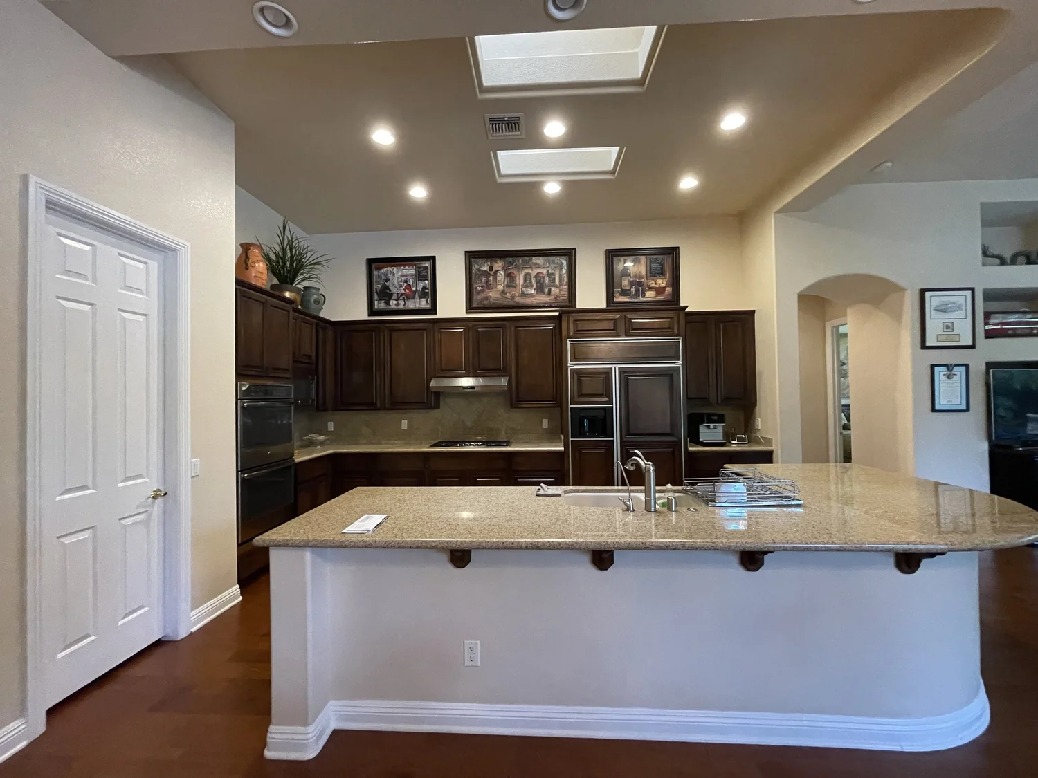Maison des Papillons kitchen before — dark raised-panel cabinetry and granite counters