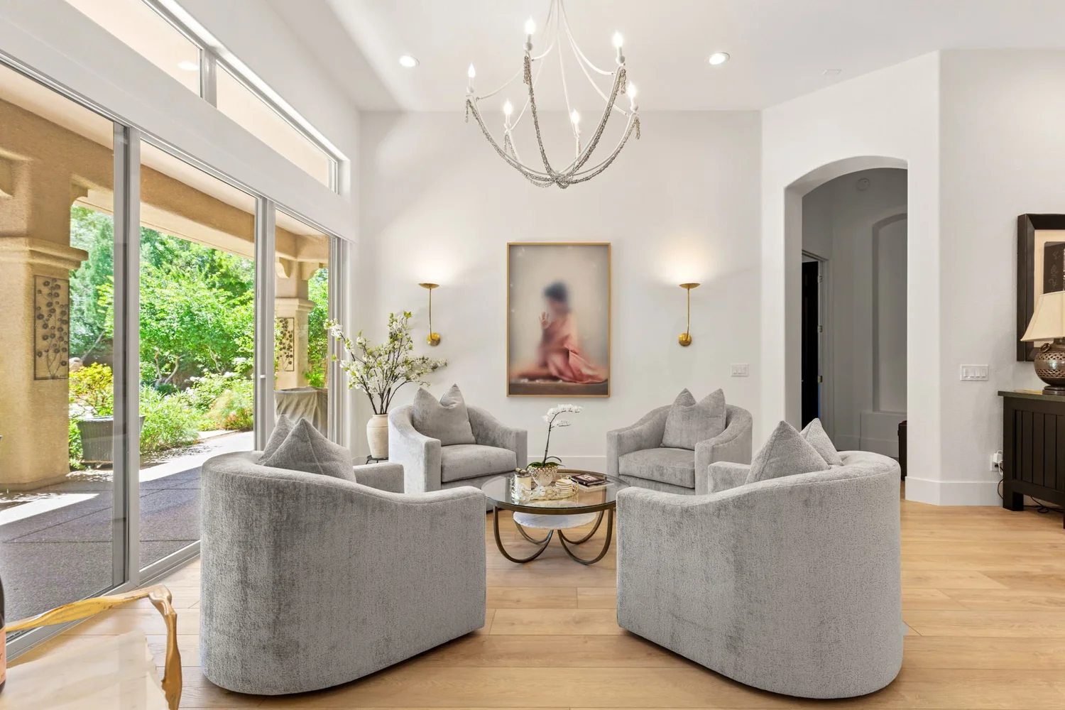 Maison des Papillons sitting room — velvet swivel chairs under a ring chandelier