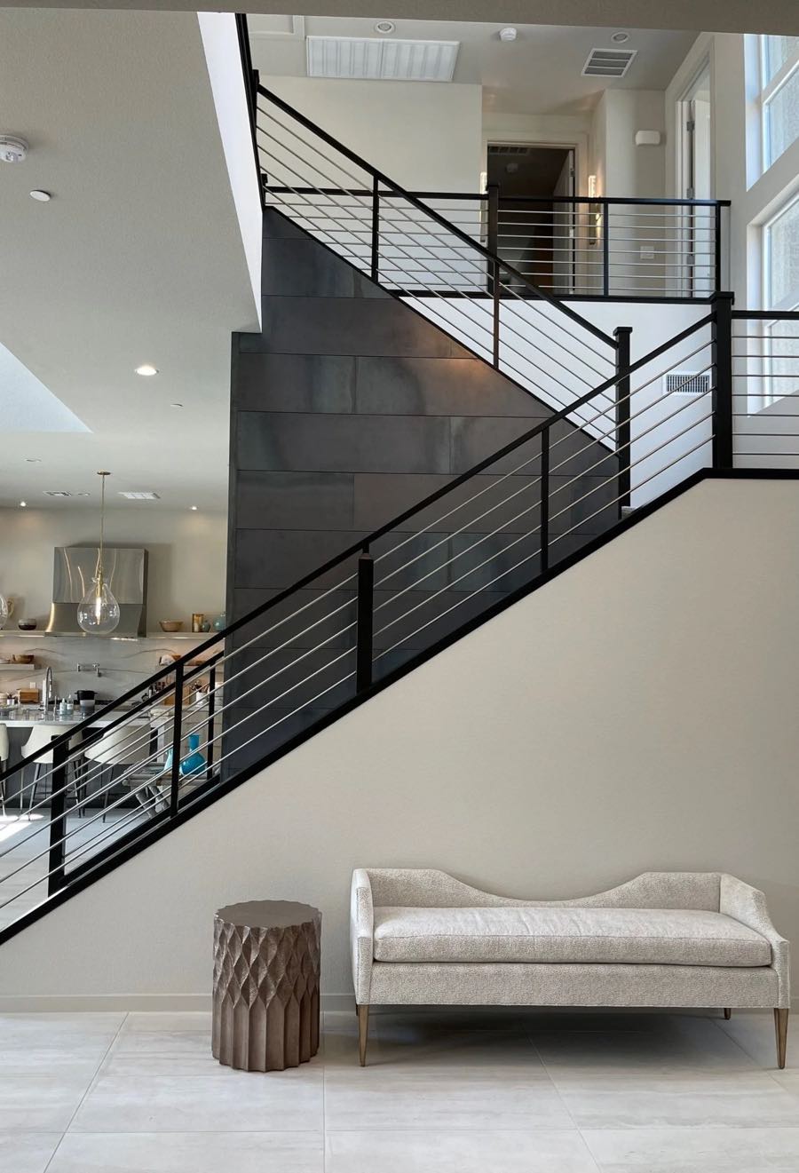 Two-story entry with black steel staircase and cream bench, designed by SK Design