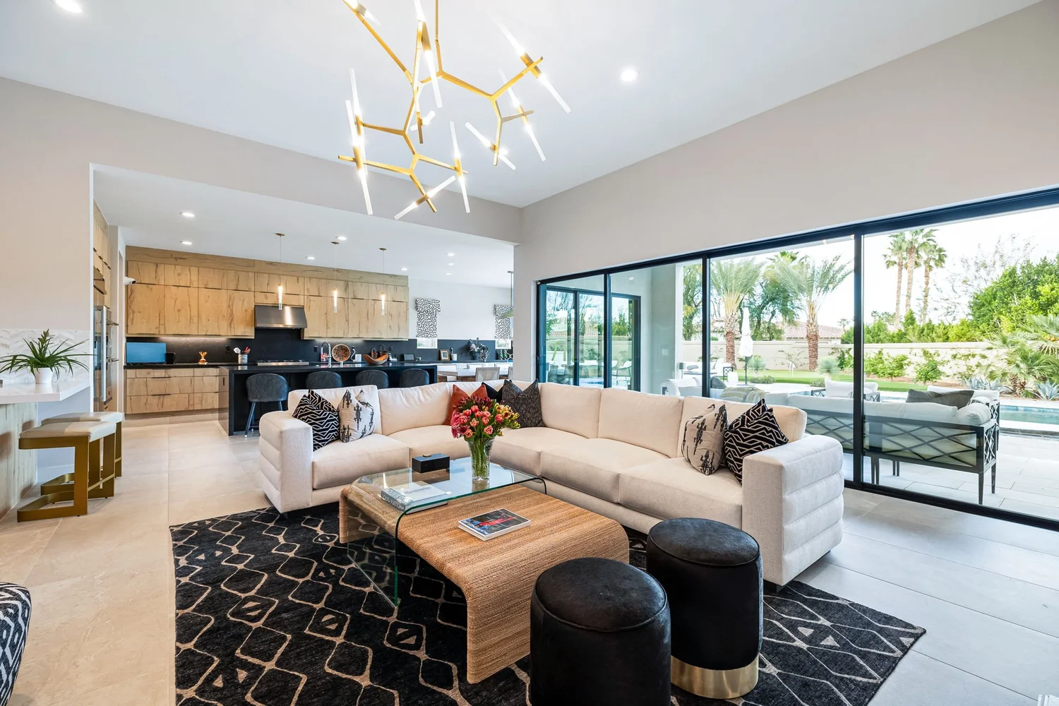 Stone Creek Trail great room — brass branch chandelier over the lounge and open kitchen